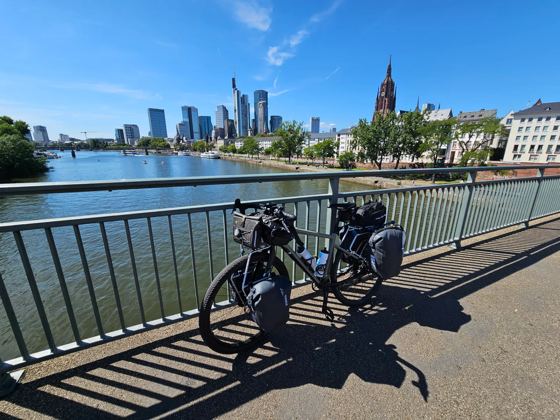 A loaded touring bike on a bridge over the Main, Frankfurt skyline behind